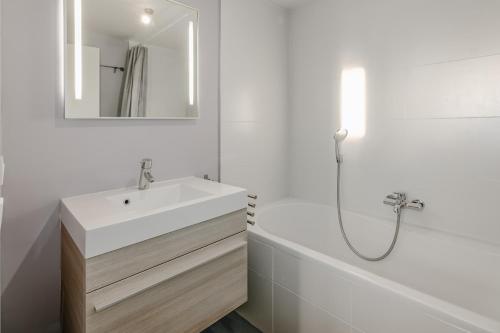 y baño blanco con lavabo y bañera. en Blinkaart 8, en Oostduinkerke