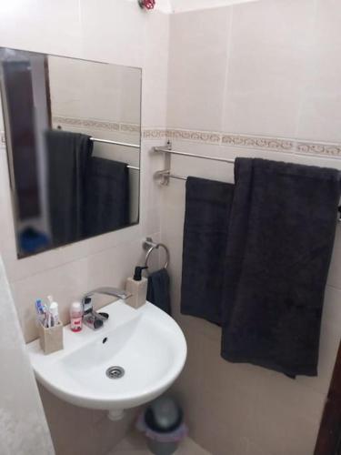 a bathroom with a white sink and black towels at Bel appartement Hay salam- agadir- Wi-Fi in Agadir