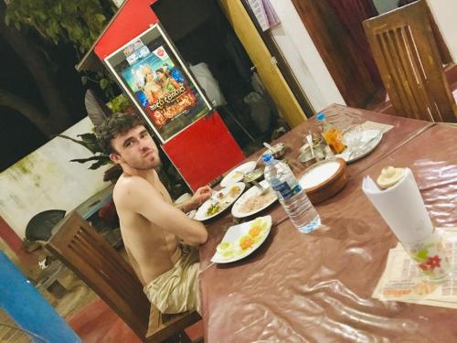 Tashil Hotel & Restaurant في تيساماهاراما: رجل يجلس على طاولة مع طبق من الطعام