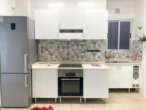 uma cozinha com armários brancos e um frigorífico de aço inoxidável em Nestor de la Torre I by Canary365 em Las Palmas de Gran Canaria