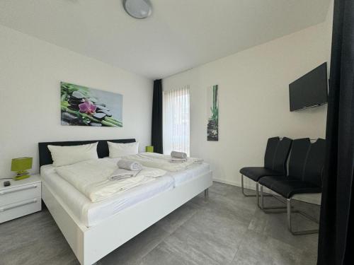 ein Schlafzimmer mit einem weißen Bett und einem Stuhl in der Unterkunft Strandloft-Frieshörn Nordsee Park Dangast in Dangast