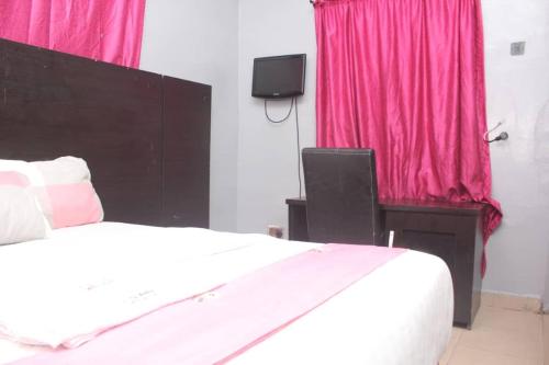 um quarto com uma cama branca e cortinas cor-de-rosa em D’ ISLAND AND CLUB HOTEL em Lekki