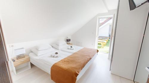 a white bedroom with a bed and a large window at Villa Four Stars ART-PE in Trebnje