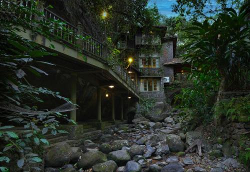 a bridge over a stream in front of a building at Mystic Mayapott, Thekkady in Thekkady