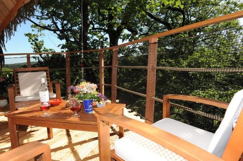 - une table en bois avec des verres de vin sur la terrasse dans l'établissement Les hébergements insolites de Quénécan, à Perret
