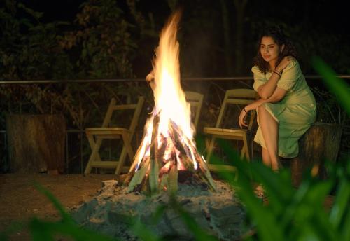 a woman sitting in front of a fire at Mystic Mayapott, Thekkady in Thekkady