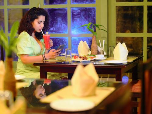 a woman sitting at a table with a drink at Mystic Mayapott, Thekkady in Thekkady