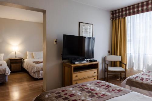 a hotel room with a flat screen tv and two beds at Hotel Nippon y Centro de Eventos in Santiago