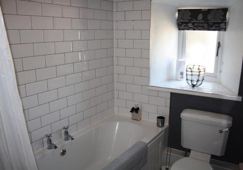 a white bathroom with a tub and a toilet at Dinmore in Richmond