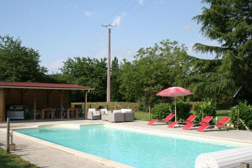 una piscina con sillas rojas y sombrilla en Domaine des Hirondelles, en Saint-Vincent-de-Cosse