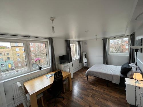 ロンドンにあるBethnal green homeのベッドルーム1室(ベッド1台、デスク、窓2つ付)