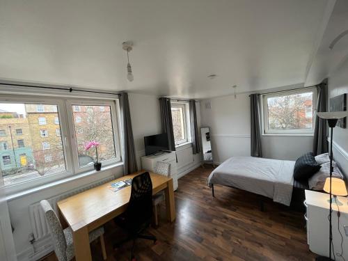 a bedroom with a bed and a desk and two windows at Bethnal green home in London