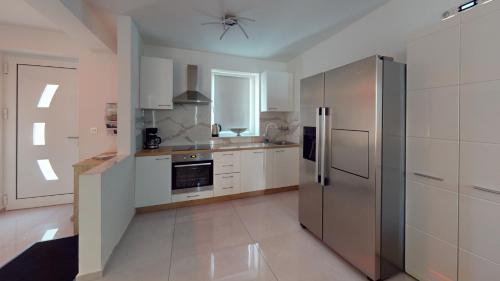 a kitchen with white cabinets and a stainless steel refrigerator at Villa Four Stars ART-PE in Trebnje