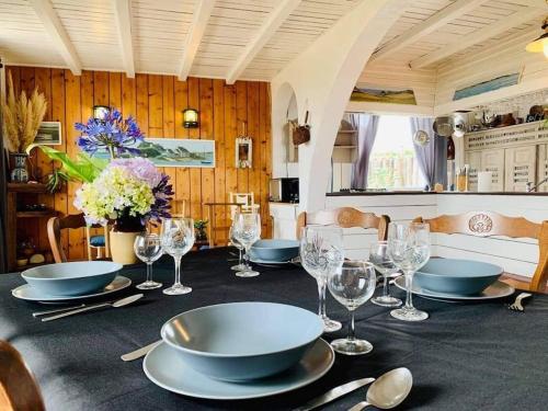 a table with plates and wine glasses on it at Gîte Les Chardons Bleus , les pieds dans l’eau in Pleubian