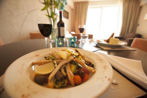a plate of food on a table with a glass of wine at Epic Hotel San Luis in La Punta