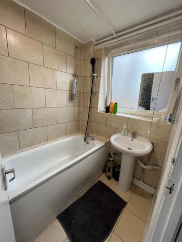 a bathroom with a white tub and a sink at Bethnal green home in London