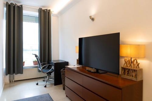 a living room with a flat screen tv on a dresser at Sunny Side - Apartment by Comfort Housing in Falkensee
