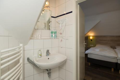 uma casa de banho com um lavatório e uma cama em Roca Restaurant und Hotel em Bommersheim