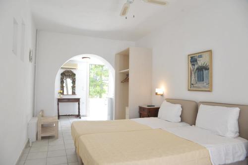 a white bedroom with two beds and a table at Medusa Beach Resort & Suites in Plaka