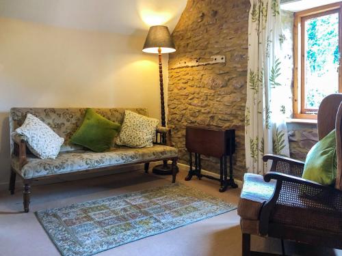 uma sala de estar com um sofá e uma parede de pedra em The Mill House em Lea