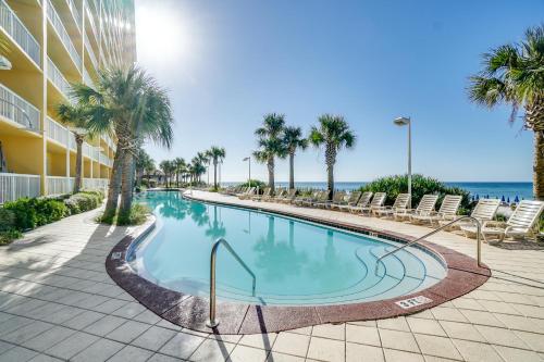 a swimming pool with chairs and the ocean in the background at Calypso Beach Resort Towers in Panama City Beach