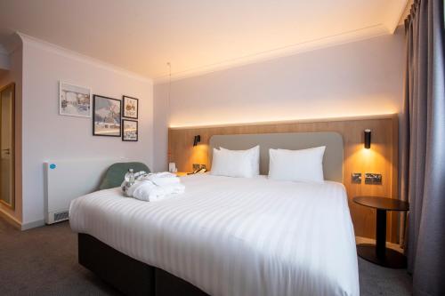 um quarto de hotel com uma cama grande com lençóis brancos em Holiday Inn Brentwood, an IHG Hotel em Brentwood
