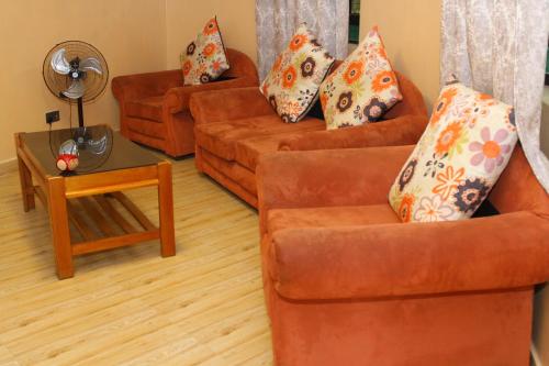 salon z 2 pomarańczowymi kanapami i stołem w obiekcie Banana Hills Haven w mieście Narok
