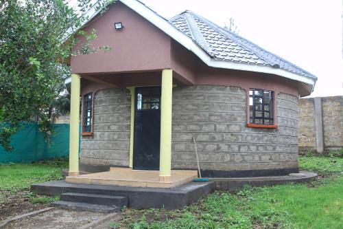 mały dom z gankiem i żółtymi kolumnami w obiekcie Banana Hills Haven w mieście Narok