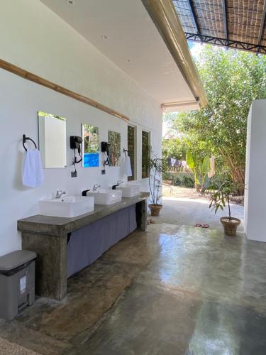 uma casa de banho com 3 lavatórios e um espelho grande em Wild Monkeys Hostel em Moalboal