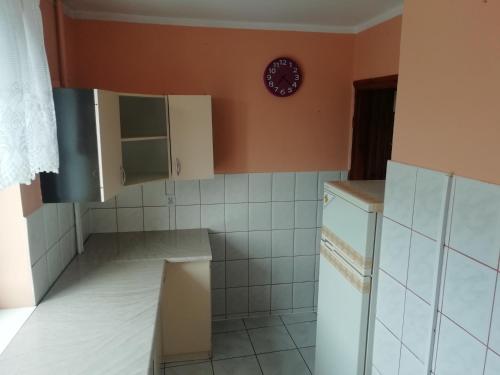 a kitchen with white tiles and a clock on the wall at Apartament Szczytno centrum in Szczytno