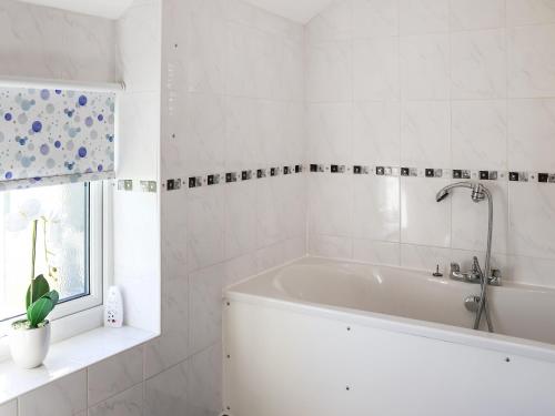 a white bathroom with a tub and a window at Bwthyn Glanllyn in Llanuwchllyn