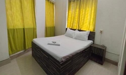 een bed in een kamer met gele en groene gordijnen bij FabExpress Avenue villa in kolkata