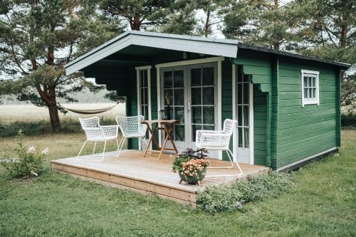 a green shed with chairs and a table on a deck at Metsatuule puhkeküla in Hiiumaa