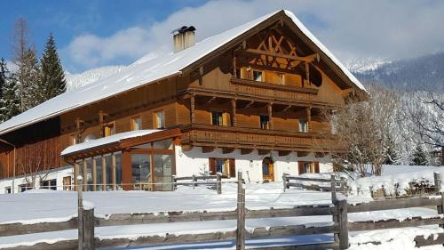 une grande maison en bois dans la neige avec une clôture dans l'établissement Bauernhaus Durrahof, à Steinberg am Rofan