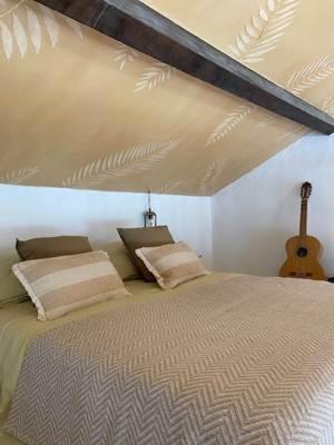 a bedroom with a large bed with a guitar at Le Mas des Perrines Maison d’Hôtes in Pernes-les-Fontaines