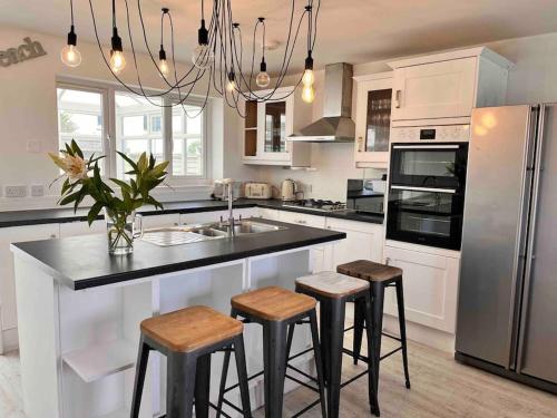 a kitchen with a large island with stools in it at Wonderful Beach House Just 250m From The Sea in Newquay