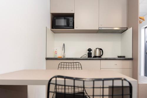 a kitchen with white cabinets and a table and chairs at Comfort Housing Apartments in Falkensee