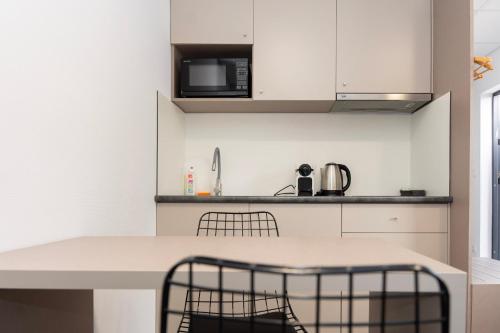eine Küche mit weißen Schränken und einem Tisch und Stühlen in der Unterkunft Comfort Housing Apartments in Falkensee