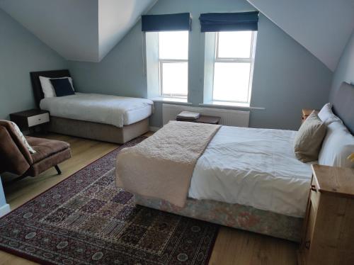 a bedroom with a bed and a chair and two windows at 4 Bayview terrace in Bundoran