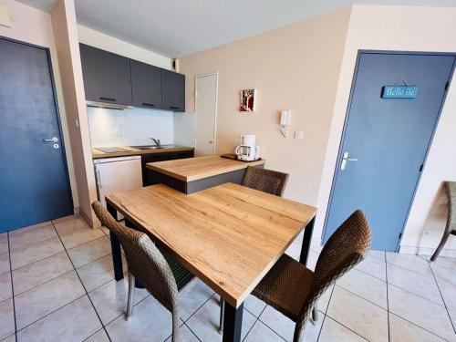 une cuisine et une salle à manger avec une table et des chaises en bois dans l'établissement Quiberon - Appartement 2P 33m² avec aperçu mer, balcon, parking et animaux acceptés - FR-1-478-112, à Quiberon