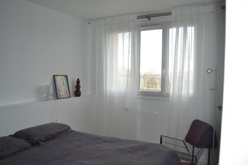 - une chambre avec un lit, une fenêtre et une chaise dans l'établissement Charmant T4 proche Paris (métro), à Ivry-sur-Seine