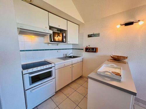 une petite cuisine avec un évier et une cuisinière dans l'établissement Maison 3 pièces avec Terrasse et Garage, proche centre de Quiberon - FR-1-478-117, à Quiberon