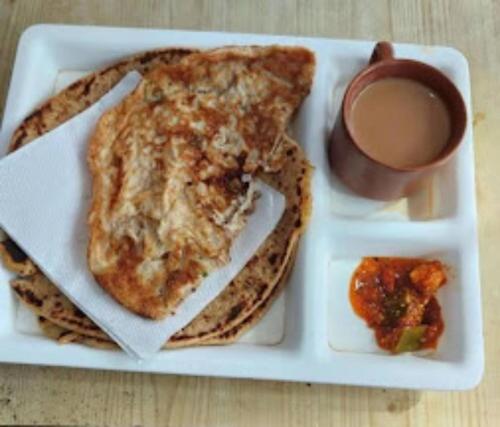 a plate of food with pancakes and a cup of coffee at Goroomgo Varanasi Paradise Varanasi in Varanasi