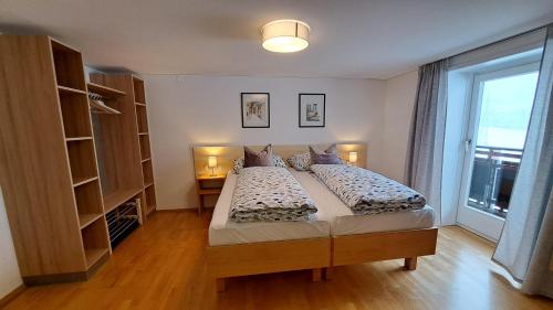 a bedroom with two beds and a large window at Ferienwohnung Pia in Wald am Arlberg