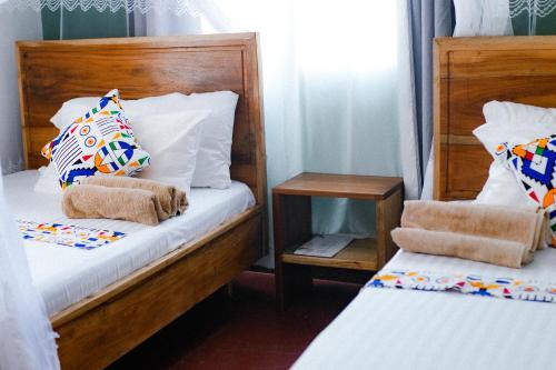 a bedroom with two beds with towels on them at Goodtimewithfar House in Moshi