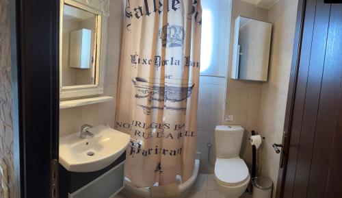 a bathroom with a sink and a toilet and a shower curtain at Araxova villa ELGREKO in Arachova