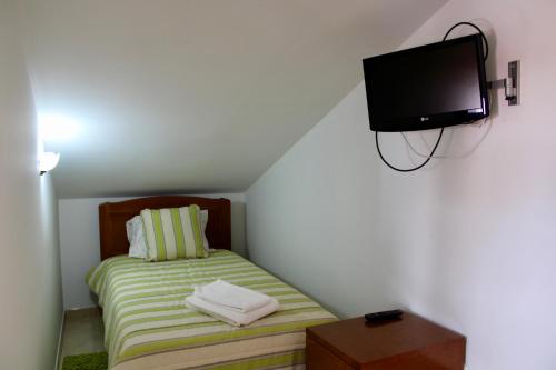 Dormitorio pequeño con cama y TV en la pared en A Casa Dos Avós, en Penha Garcia