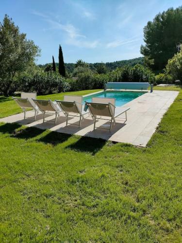 un groupe de chaises assises à côté d'une piscine dans l'établissement Le bastidon de Sanary- piscine et jardin paysagé., à Sanary-sur-Mer
