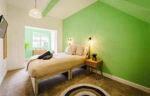 een groene slaapkamer met een bed en een groene muur bij Rise Duplex Apartments - Market Harborough in Market Harborough