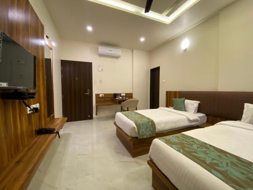 um quarto de hotel com duas camas e uma televisão de ecrã plano em The Grand Sarovar Inn And Suites em Chākan